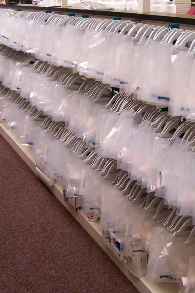 Numerous see-thru poly storage bags with medications hanging in a pharmacy