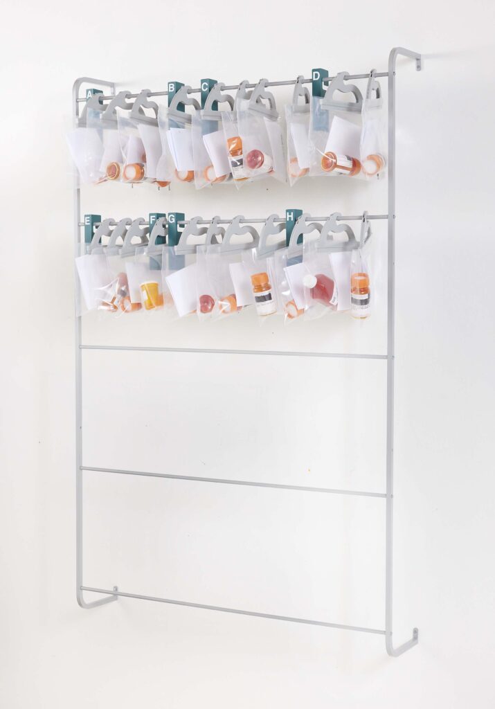 Anodized aluminum wall rack for hanging multi-use see-through poly storage bags – example bags hold pharmacy prescriptions