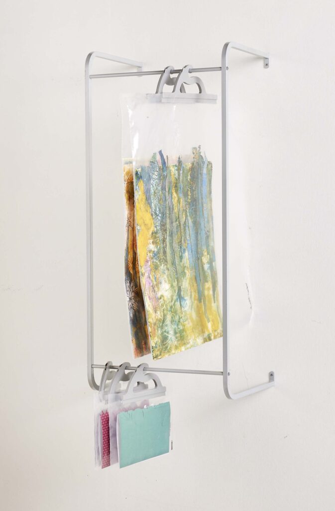 Anodized aluminum wall rack for hanging multi-use see-through poly storage bags – example bags hold artwork